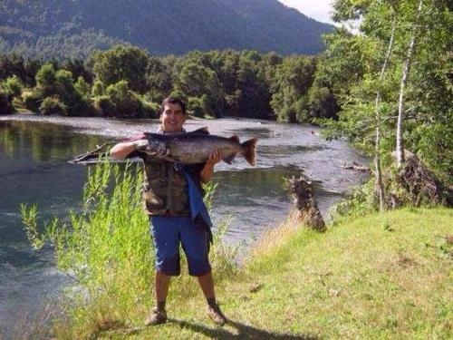a man holding a fish in front of a river at Cabañas Los Canelos Hermosa granja en Pucón in Pucón