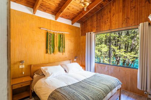 a bedroom with a bed and a large window at Cabañas Rápidos del Río Baker in Puerto Bertrand