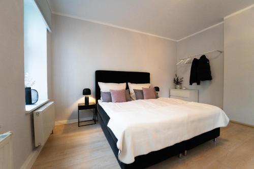 1 dormitorio con 1 cama blanca grande con almohadas rosas en Charles & Kätchen living Gohlis, en Leipzig