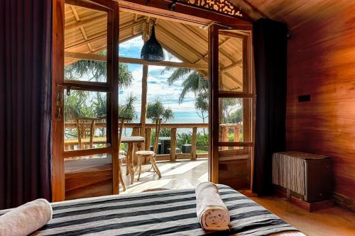 Schlafzimmer mit einem Bett und einer großen Glastür in der Unterkunft Sea View Clay House in Hiriketiya