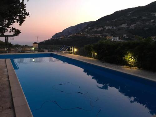 a large swimming pool with a sunset in the background at Residence Le Villette in Ravello