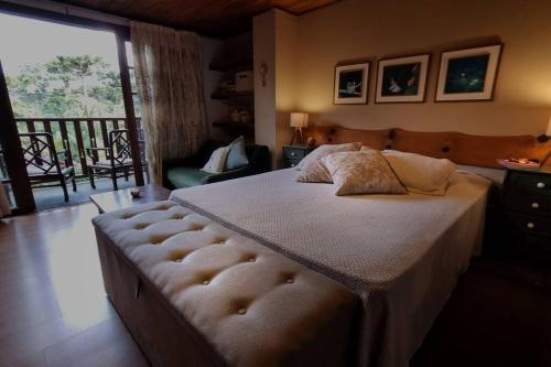 1 dormitorio con 1 cama grande y balcón en Chalé Pedra do índio - no coração de Maringá MG, en Bocaina de Minas