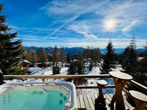 a hot tub on a deck with snow covered mountains at Almhütte Kärnten in Maltaberg