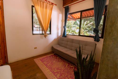 a living room with a couch and two windows at Hostel Villa Vento Surf in Santa Catalina