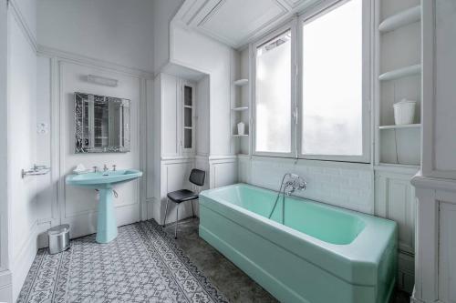 La salle de bains est pourvue d'une baignoire bleue et d'un lavabo. dans l'établissement La Maison Rouge - Maison Familiale & Proche centre, à Vichy