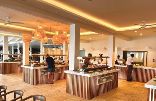 two people standing at the counter of a restaurant at Coral Azur Beach Resort Mont Choisy in Mont Choisy