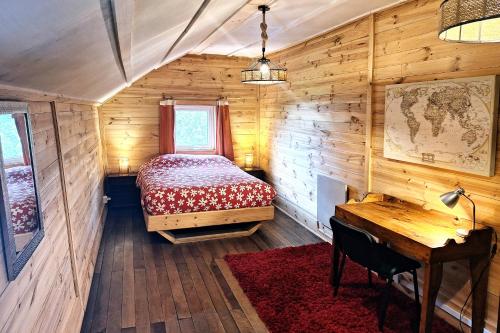 a bedroom in a wooden cabin with a bed and a desk at MaPatagonia Hostel Monumento Nacional in Puerto Varas