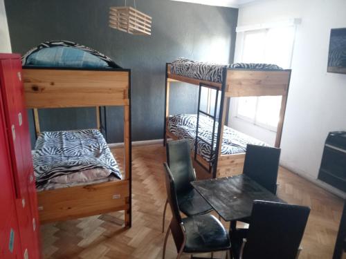a room with two bunk beds and a table and chairs at Hostal Salvador in Santiago