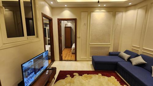 a living room with a blue couch and a tv at 3rd floor luxury apartment-families only in Alexandria