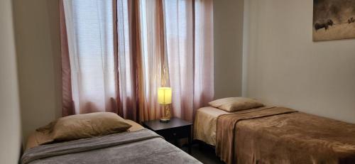Cette chambre comprend deux lits et une lampe sur une table. dans l'établissement Urban Oasis: Stylish House, short drive to airport, 