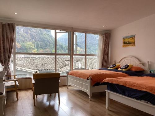 a bedroom with two beds and a large window at Lazzy inn in Yangshuo