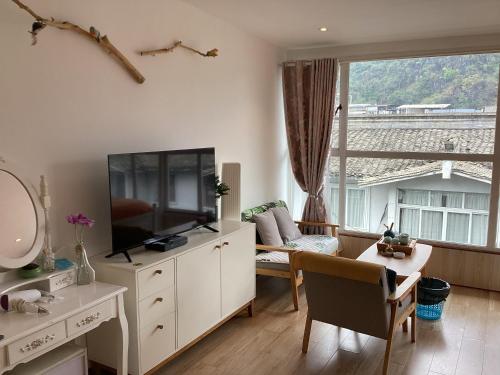 a living room with a tv and a table and a couch at Lazzy inn in Yangshuo