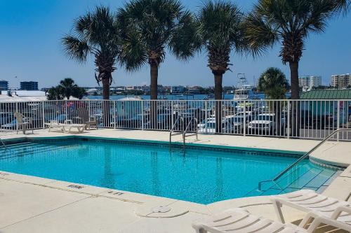 a swimming pool with chairs and palm trees at Barataria 204 in Destin