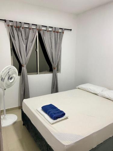 a bedroom with a bed with a fan and a window at Acogedor Apartamento Cercano al Aeropuerto Ernesto Cortissoz in Malambo