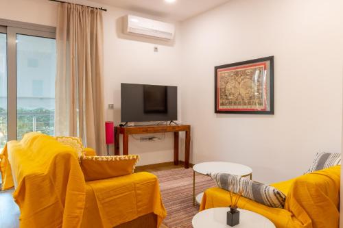 uma sala de estar com mobiliário amarelo e uma televisão de ecrã plano em Academia apartments by the park em Atenas