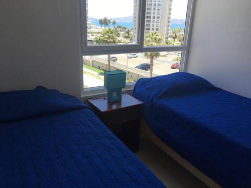 a bedroom with two beds and a large window at Amplio dpto a pasos de la playa. in Coquimbo