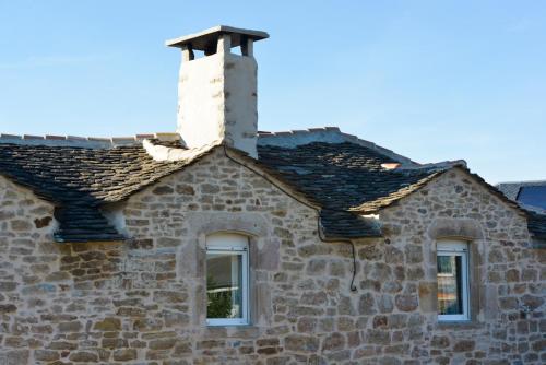 a stone building with a chimney and two windows at Les Caselles, Gîte et Chambre d'hôtes in Saint-Beauzély