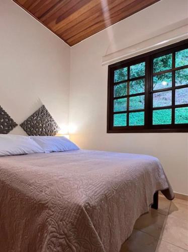 1 dormitorio con 1 cama grande y 2 ventanas en CasaComVida pousada en Santo Antônio do Pinhal