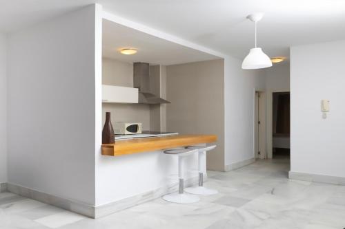 a kitchen with white walls and a counter and stool at Palacio de Luja in El Puerto de Santa María