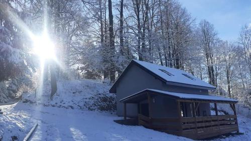 una pequeña cabaña en la nieve con el sol brillando en Domki przy Skarpie, en Lądek-Zdrój