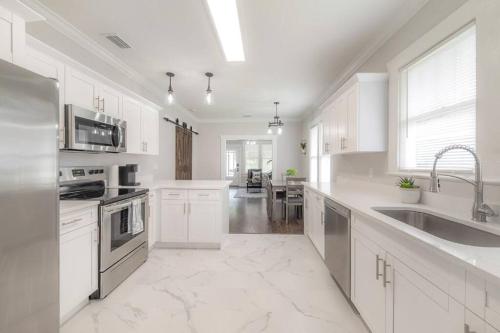 a white kitchen with white cabinets and a sink at Rustic Bungalow Near Downtown/ Foodie Hotspots in Tampa