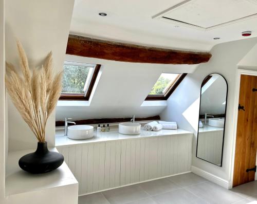 uma casa de banho com dois lavatórios e dois espelhos em The Manor at Abberley em Abberley