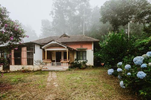 a small house with a porch in the fog at Stream Garden Mountain Resort in Kalpetta