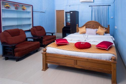 a bedroom with a bed with red pillows and two chairs at Stream Garden Mountain Resort in Kalpetta