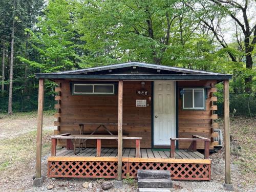 a wooden cabin with a porch and a table at Nasu Takahara Auto Campsite - Vacation STAY 42066v in Nasushiobara