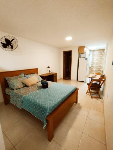 a bedroom with a bed and a kitchen with a table at kitnet Praia do Morro Guarapari in Guarapari