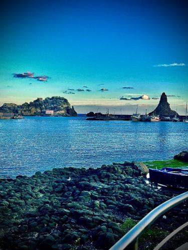 a large body of water with rocks and boats on it at LAVIKA - Luxury Holiday Home in Acitrezza