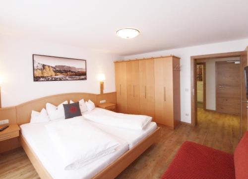 a bedroom with a white bed and a cabinet at Alpenapartments Unterschlag in Annaberg im Lammertal