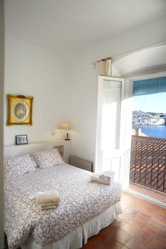 a white bedroom with a bed and a large window at Casa Flora - Cadaqués in Cadaqués