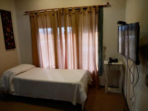 Schlafzimmer mit einem Bett und einem Fenster mit Vorhängen in der Unterkunft Daily Suites Hotel Boutique in Puerto San Julian