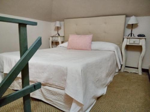 Daily Suites Hotel Boutique في بورتو سان جوليان: غرفة نوم عليها سرير ومخدة وردية