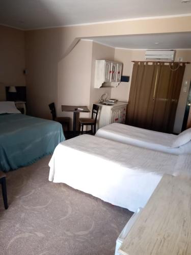 ein Hotelzimmer mit 2 Betten und einem Tisch in der Unterkunft Daily Suites Hotel Boutique in Puerto San Julian
