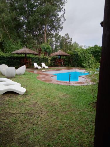 a swimming pool with chairs and umbrellas in a yard at Daily Suites Hotel Boutique in Puerto San Julián