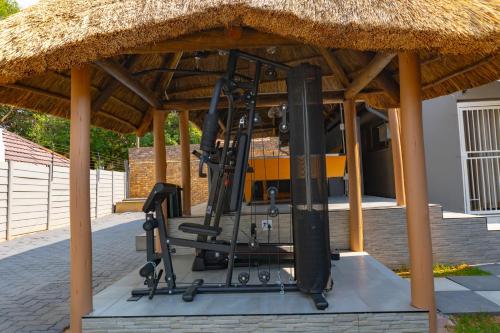 a gym under a thatched roof with exercise equipment at Homes of Ace Gold in Pretoria