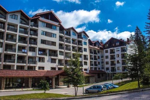 a large apartment building with cars parked in front of it at Apartment B45 Borovets Gardans in Borovets