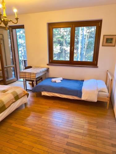 a bedroom with two beds and a table and windows at Villa Esclusiva a 3 Piani in Bardonecchia