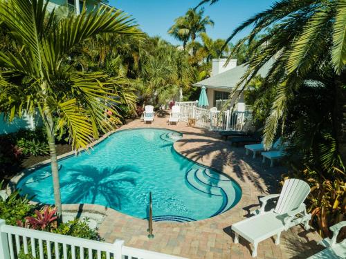 a swimming pool with palm trees and a house at Anna Cabana Bungalow #1 in Holmes Beach