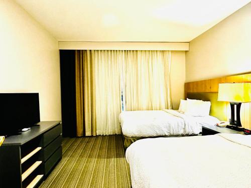 a hotel room with two beds and a flat screen tv at Radiant Inn and Suites in Murfreesboro