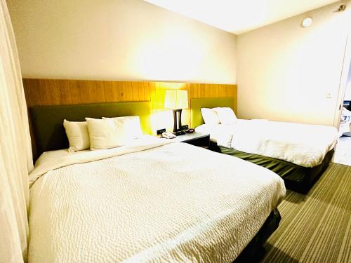 a hotel room with two beds with white sheets at Radiant Inn and Suites in Murfreesboro