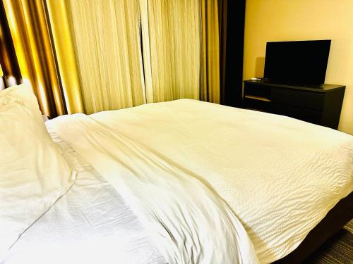 a bedroom with a white bed and a television at Radiant Inn and Suites in Murfreesboro