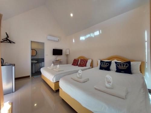 a bedroom with two beds and a television in it at Raintrary House in Nakhon Phanom