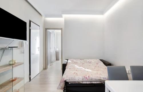 a white bedroom with a bed and a mirror at Casa Sanremo Tiziano in Sanremo