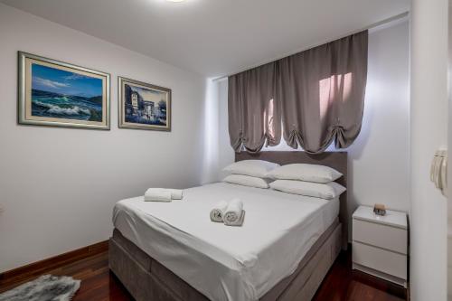 um quarto com uma cama com lençóis brancos e uma janela em Noemi Luxury Apartment em Solin