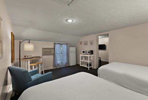 een hotelkamer met 2 bedden en een blauwe stoel bij Traverse Bay Inn in Traverse City