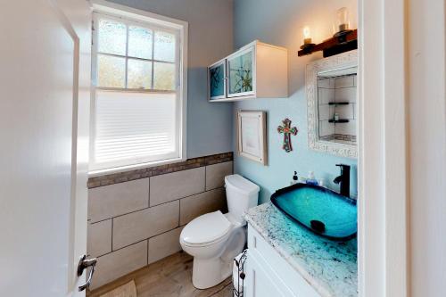 La salle de bains est pourvue d'un lavabo bleu et de toilettes. dans l'établissement Red Door Cottage, à Waco