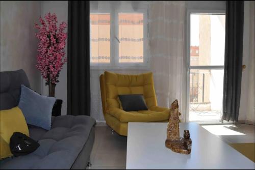 sala de estar con sofá y silla amarilla en Charmante location ensoleillée en Argel